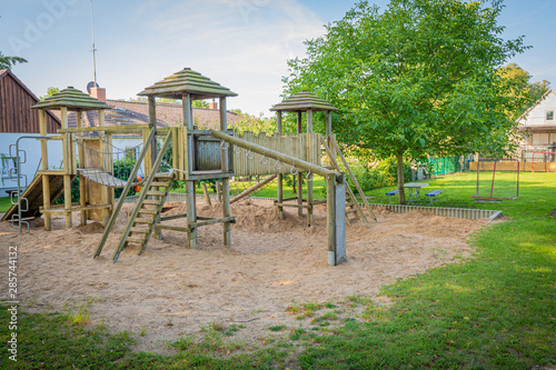 a wooden climbing frame stands on the premises of a kindergarten