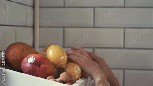 beautiful woman picking out fruit from a shelp for a fruit basket that she is making as a gift photo