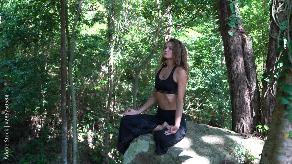 Young caucasian brunette girl is meditating in nature at tropical garden in summer, Thailand, close up Young caucasian brunette girl is meditating in nature at tropical garden in summer, Thailand, close up