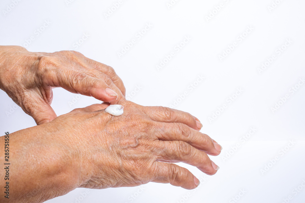 Fototapeta premium Senior Woman applying moisturising cream on her hands isolated on white background, Asian beauty skin concept