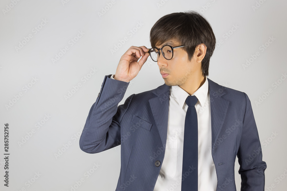 Young Asian Portrait Businessman in Navy Blue Suit Touch Eyeglasses and Look Below Young Asian Portrait Businessman in Navy Blue Suit Touch Eyeglasses and Look Below