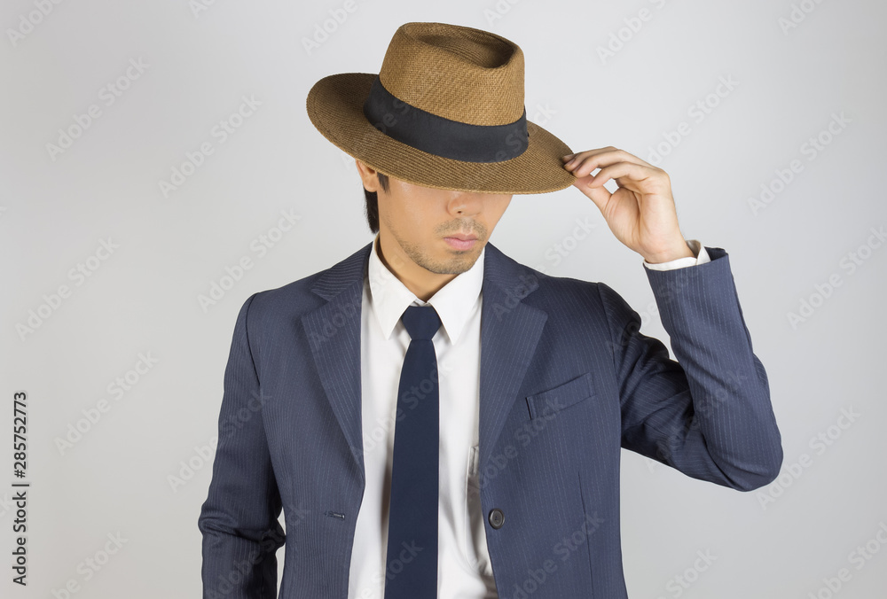 Young Asian Portrait Businessman in Navy Blue Suit Touch Hat Brim at Front View Young Asian Portrait Businessman in Navy Blue Suit Touch Hat Brim at Front View