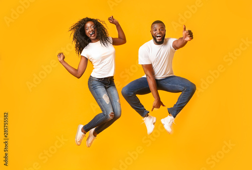 Black young couple having fun on yellow studio background