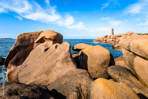 The Ploumanac'h lighthouse, named Mean Ruz, on the Pink Granite Coast in northern Brittany on the municipality of Perros-Guirec, France, with large pink granite rocks in the foreground.