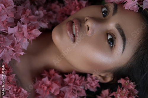 Fototapeta Naklejka Na Ścianę i Meble -  Asian girl portrait face in pink flowers. Beautiful Balinese women. Beauty salon and massage spa concept