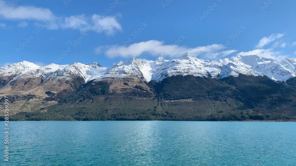Panoramic view of the lake and snowy mountains in the background on a sunny day Panoramic view of the lake and snowy mountains in the background on a sunny day