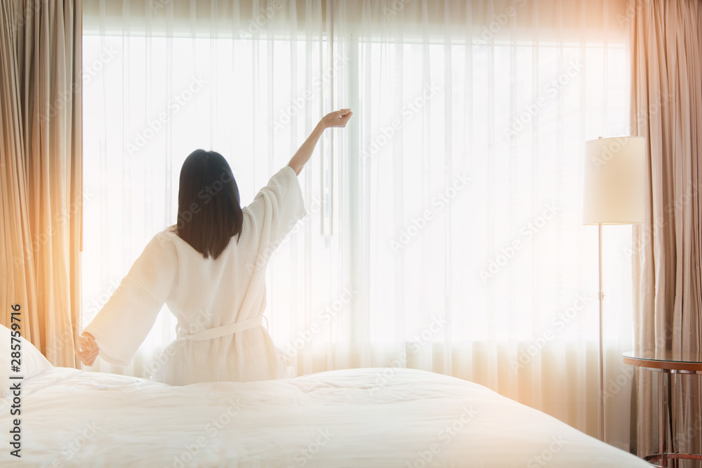 custom made wallpaper toronto digitalWoman stretching in bed after waking up, back view. Woman sitting near the big white window while stretching on bed after waking up with sunrise at morning, back view.