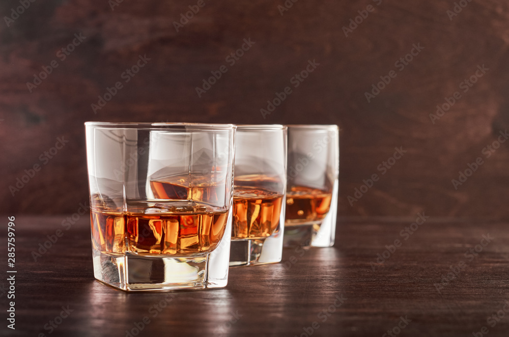 Glass of whiskey on a wooden tableTwo glasses of whisky with ice on a wooden table Glass of whiskey on a wooden tableTwo glasses of whisky with ice on a wooden table