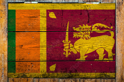 National flag of Sri Lanka on a wooden wall background.The concept of national pride and symbol of the country.Flag painted on a wooden fence with metal nails.