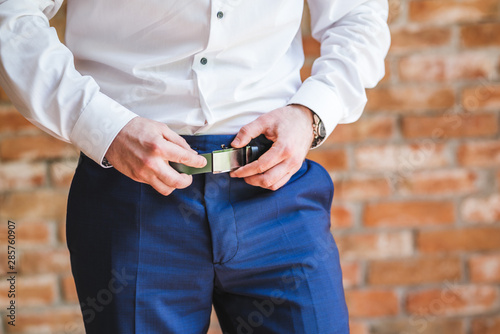 Man Putting On A Belt. Brick wall background