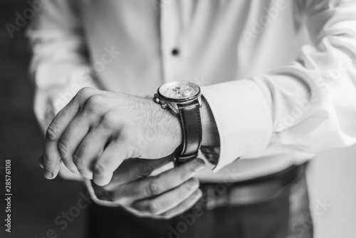 Man with a white shirt putting on a watch. Preparation. Formal wear. 
