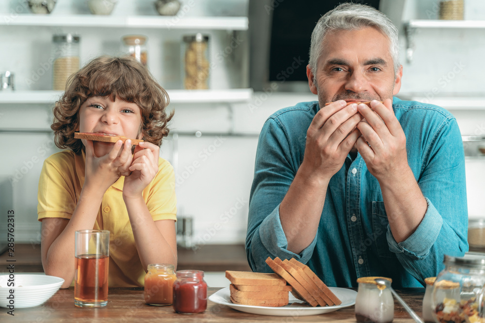 Happy father and kid eating breakfast at kitchen Happy father and kid eating breakfast at kitchen