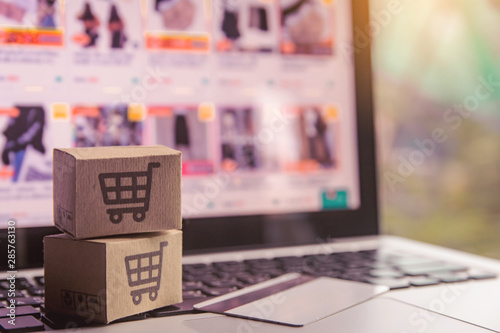 Online shopping - Paper cartons or parcel with a shopping cart logo and credit card on a laptop keyboard. Shopping service on The online web and offers home delivery.