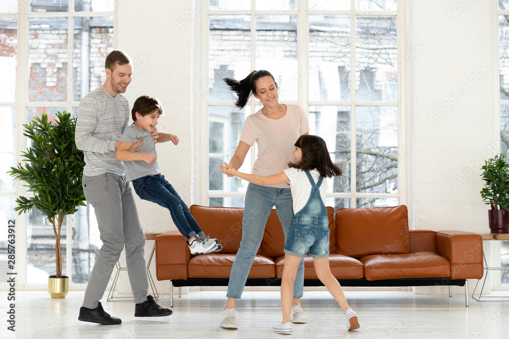 Happy parents and children laughing dancing together in living room Happy parents and children laughing dancing together in living room