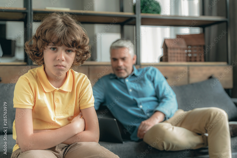 Unhappy son sitting near father on couch