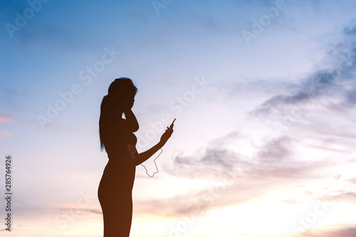 silhouette woman standing and listening music