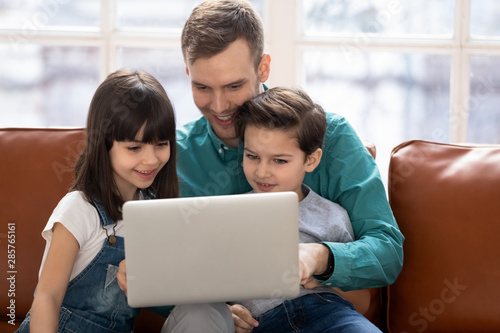 Cute small kids learning using laptop watching cartoons with dad