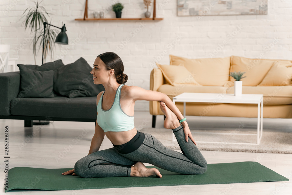 Obraz premium Smiling female stretching legs indoors stock photo
