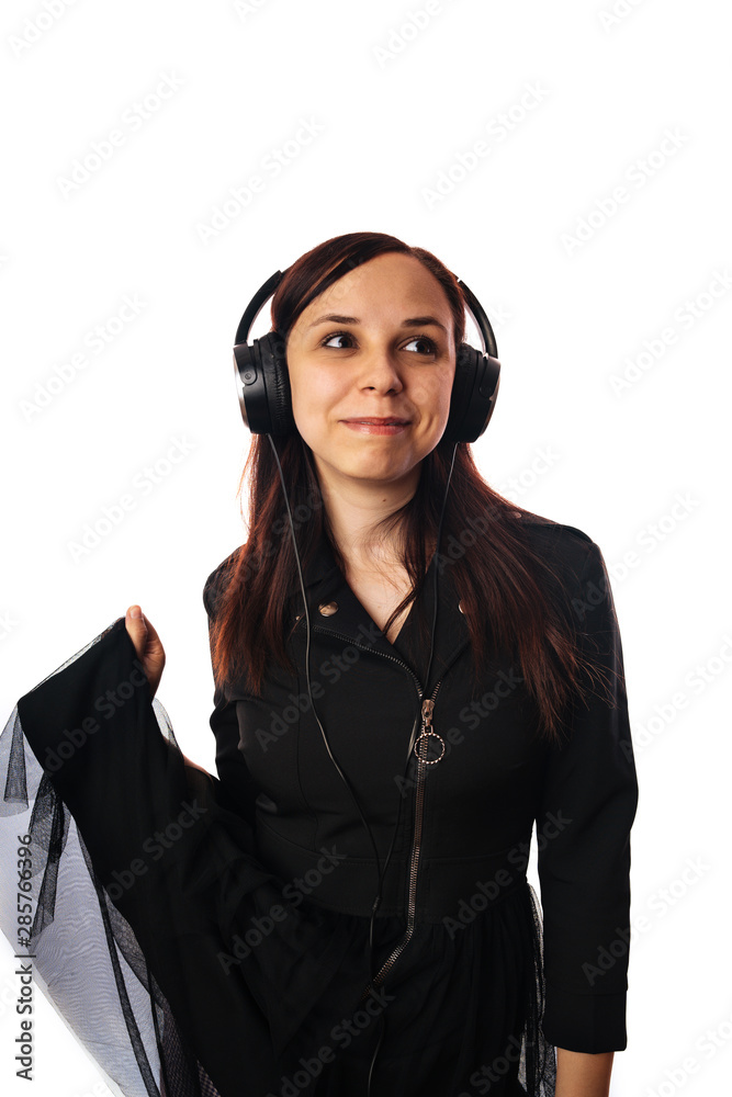 A beautiful young woman in headphones is dancing isolated on white background. The concept of International Music Day. A beautiful young woman in headphones is dancing isolated on white background. The concept of International Music Day.