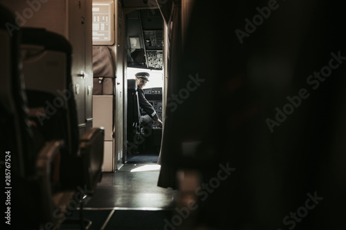 Adult pilot in uniform sitting in cabin of airplane