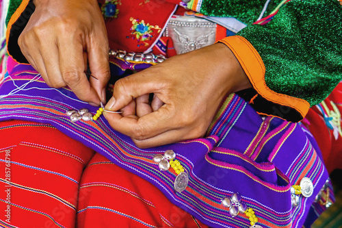 Closeup hands of Thailander Hill tribe ladies are demonstrating the sewing and decorating of costumes for tourists in her village. photo