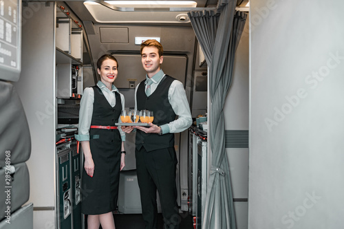 Smiling flight attendant with pilot posing for camera photo