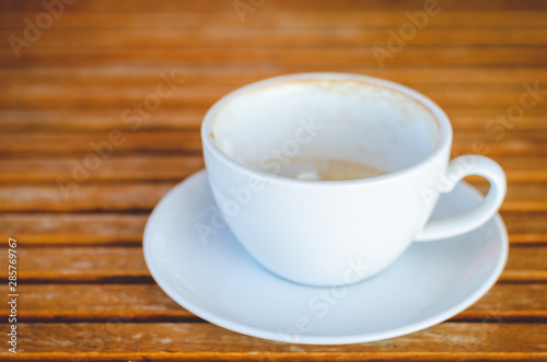 close up modern hot black coffee the cappuccino on wood background with coffee bubble foam pattern and texture in empty white cup looking and feel so delicious on glasses table in coffee shop.
