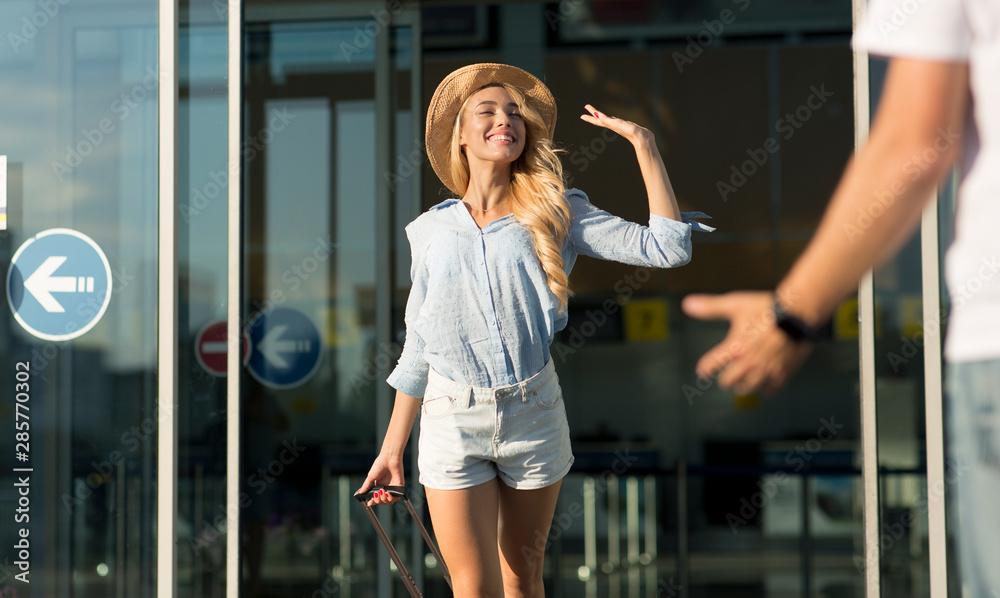 Man meeting girlfriend near airport entrance outdoors