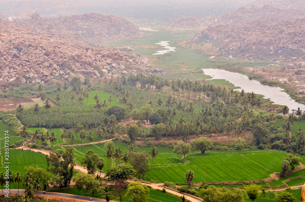 Distant and misty view of rice fields and the river in Hampi, India