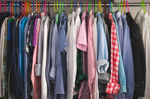 Close-up of hangers with different fashionable clothes. Children's clothes of different colors are hung on hangers in the wardrobe room. Shirts, T-shirts and other children's clothing