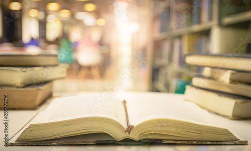 Open textbooks on reading desk in blurred library room  background