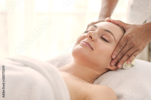 Beautiful young woman relaxing with hand massage at beauty spa. Face massage. Closed up of young beautiful woman getting spa massage treatment at beauty spa salon.
