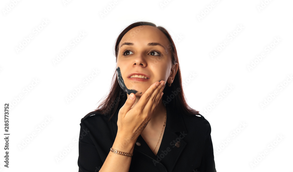 A young woman inflicts a black mask on the face isolated on white background.The concept of healthy lifestyle, beauty, body care. A young woman inflicts a black mask on the face isolated on white background.The concept of healthy lifestyle, beauty, body care.