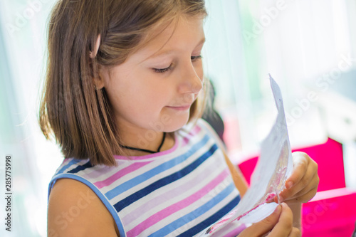 little girl embroider a cross-stitch drawing