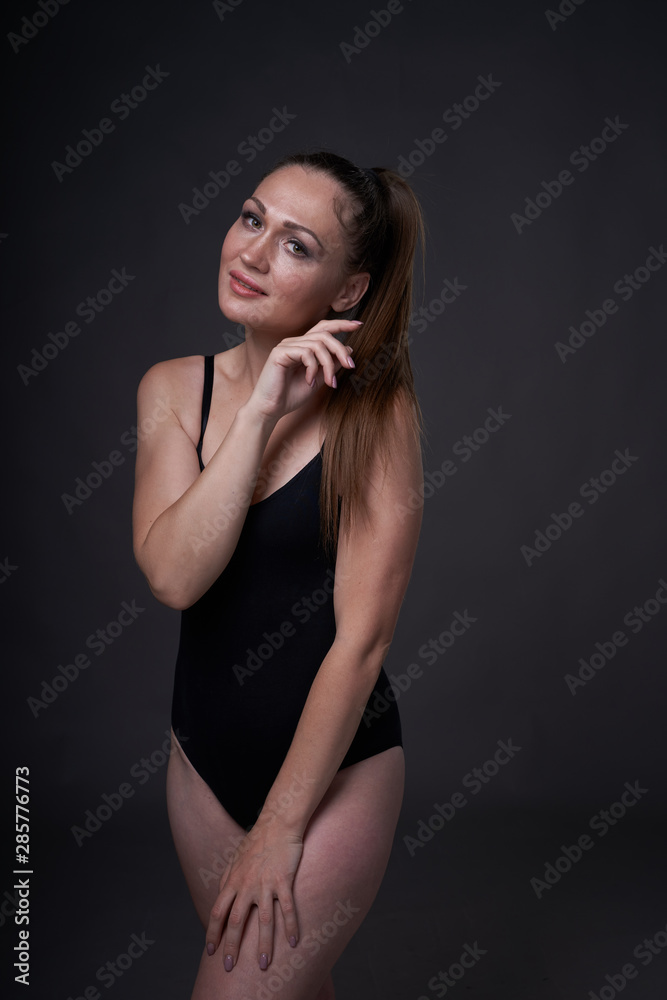 flexible sexy girl poses on a black grey background in the fitting clothes baud