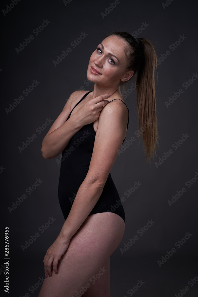 flexible sexy girl poses on a black grey background in the fitting clothes baud