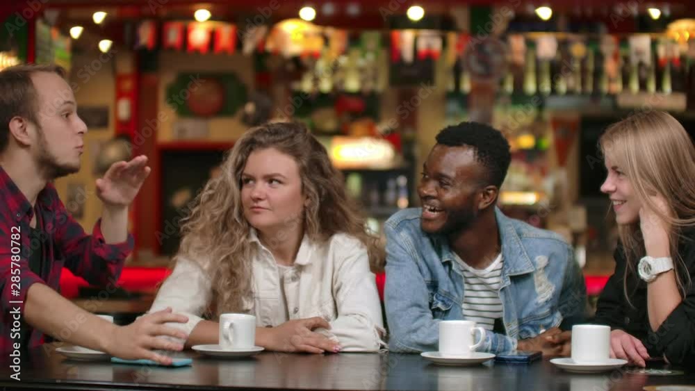 A group of drears laughing at a joke while sitting at a bar and drinking coffee together A group of drears laughing at a joke while sitting at a bar and drinking coffee together