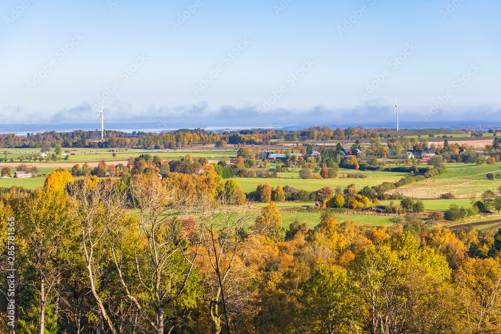 Autumn colored deciduous forest with a view of a rural landscape
