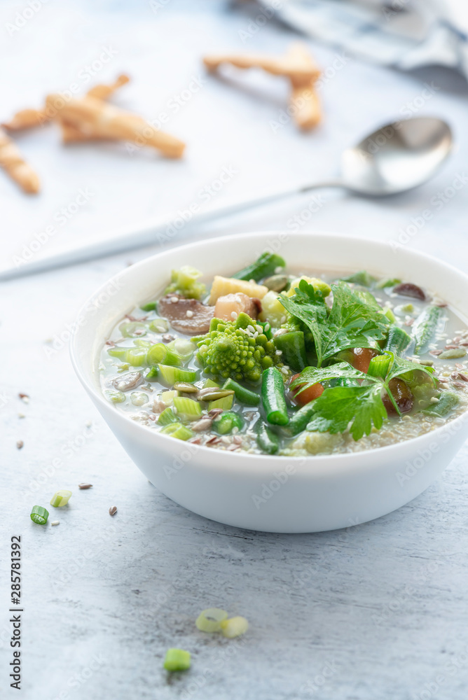 Vegetarian vegetable soup with quinoa and sesame seeds in a white bowl on the table. Tasty vegan soup, healthy eating concept. Vegetarian vegetable soup with quinoa and sesame seeds in a white bowl on the table. Tasty vegan soup, healthy eating concept.