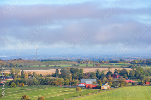 Farms and fields in a rural landscape view with a wind turbine