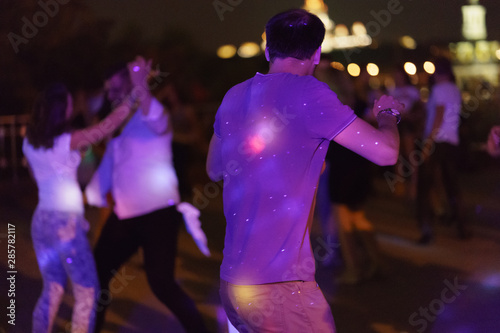 Photography of dancing people on the night party in the city street in summer night. Leisure, happiness and entertainment theme.