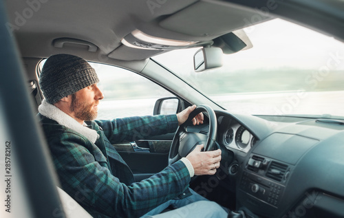 Warm dressed Bearded Man driving a new modern auto. Inside car view. © Soloviova Liudmyla