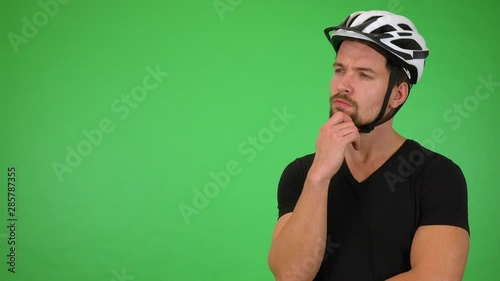 A young handsome cyclist thinks about something - green screen studio