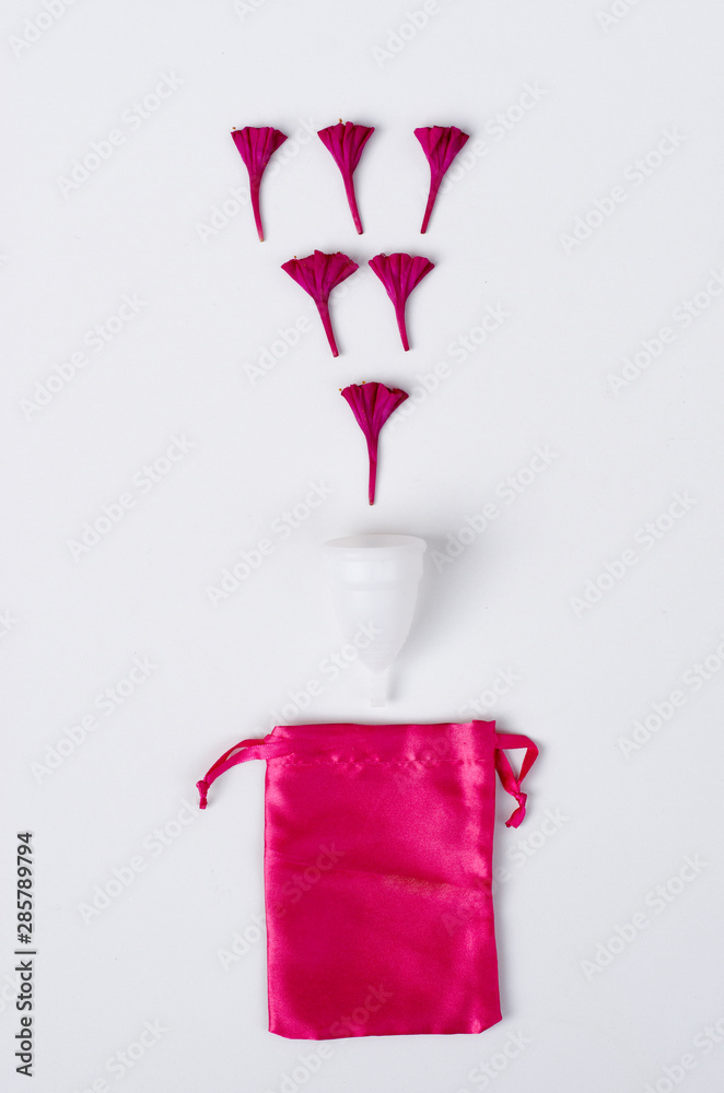 Close up of woman hand holding white menstrual cup sanitary napkin tampon on pink background health qynecology concept 