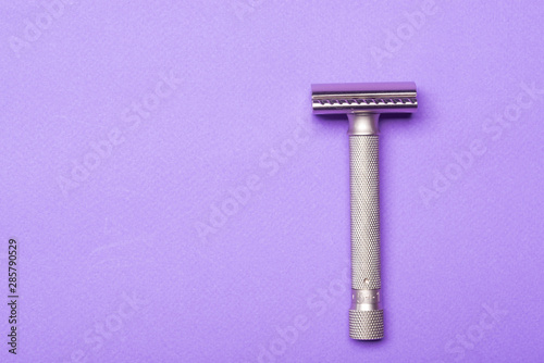 Metallic safety razor on purple background 