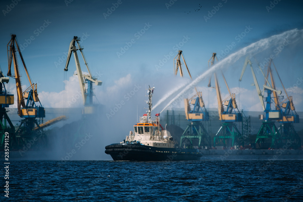 A firefighter floating modern tug boat sprays jets of water