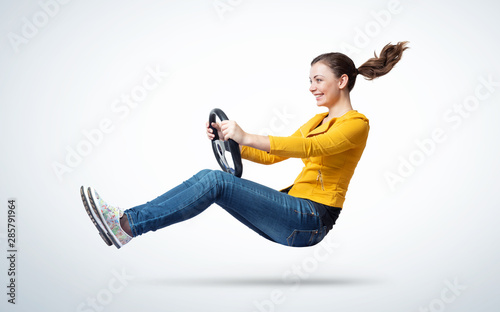 Young happy smiling girl drives a car with steering wheel in hands, auto concept  photo