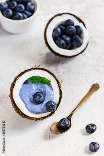 Blue matcha smoothie with berries and fruits in a coconut.