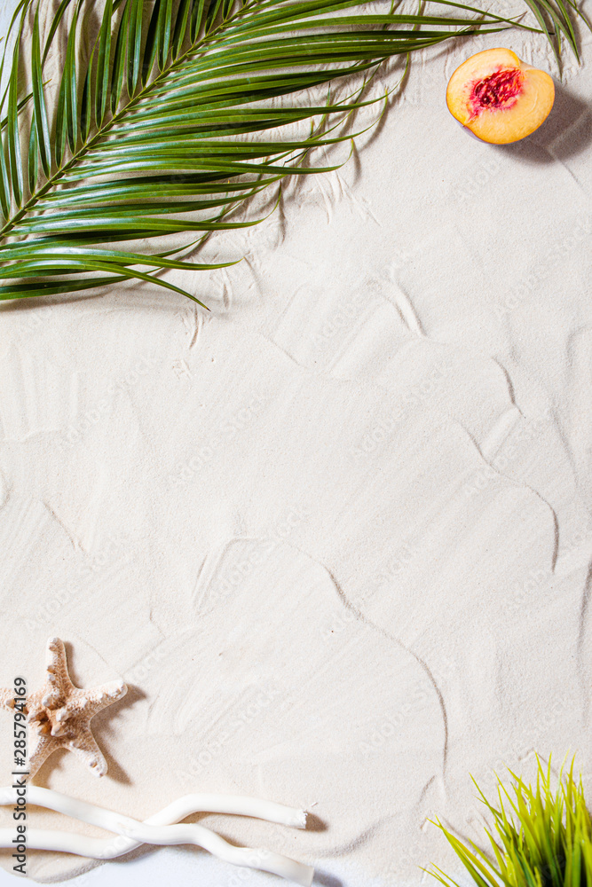 Obraz premium Beach vacation. A palm leaf, starfish, and white tree branch and juicy fruits lie on white fine sand. Desktop wallpaper.