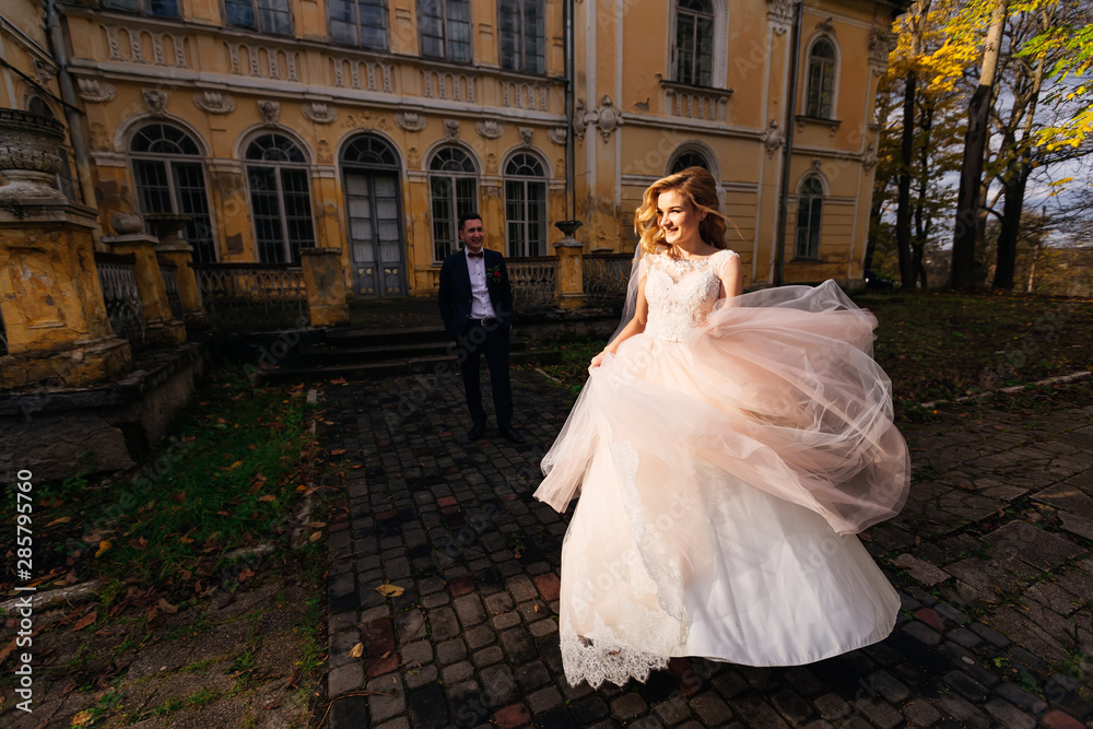 Bride in wedding dress running on pavement. groom on the backgro Bride in wedding dress running on pavement. groom on the backgro